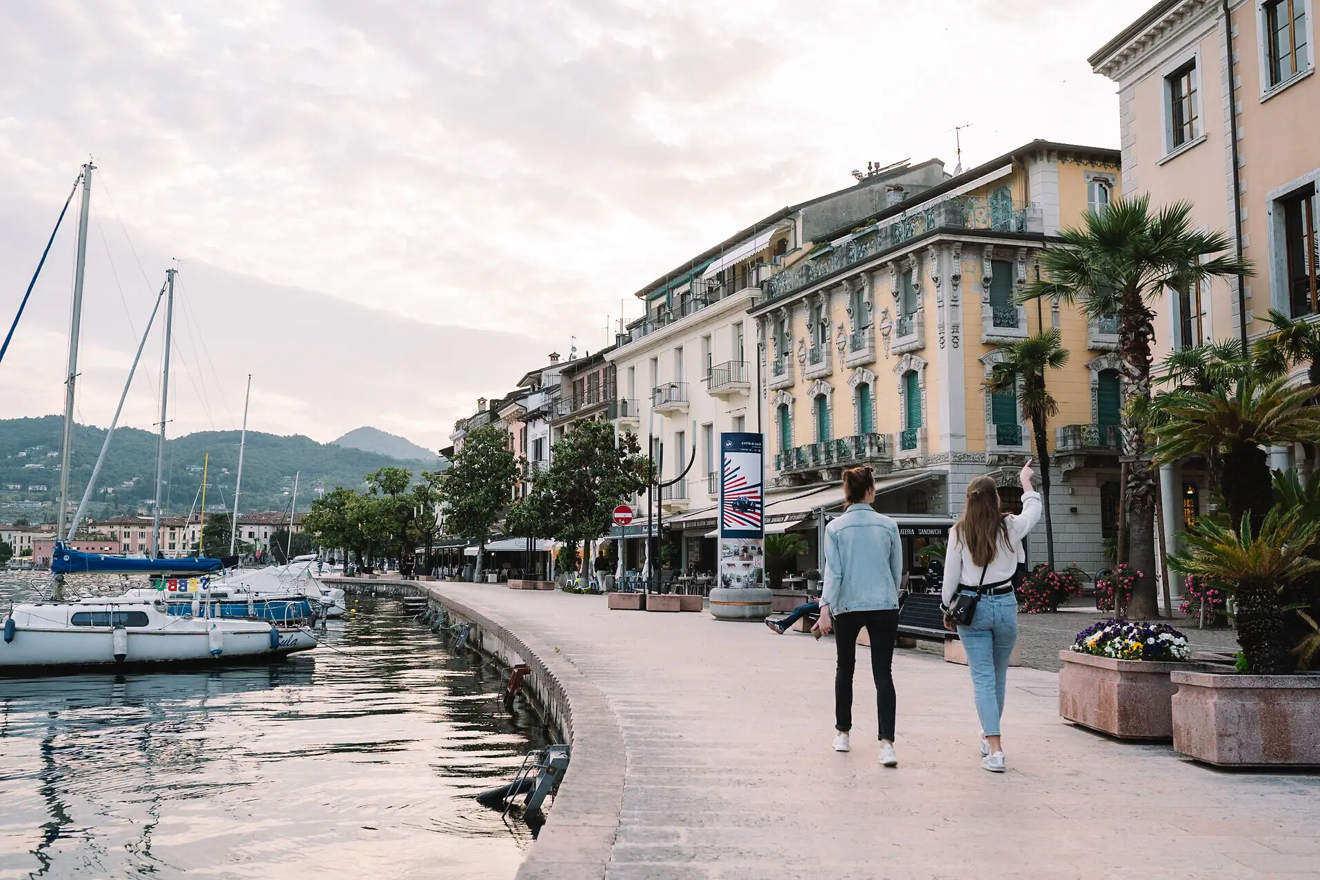 Due persone camminano su un marciapiede accanto a un corpo d'acqua.