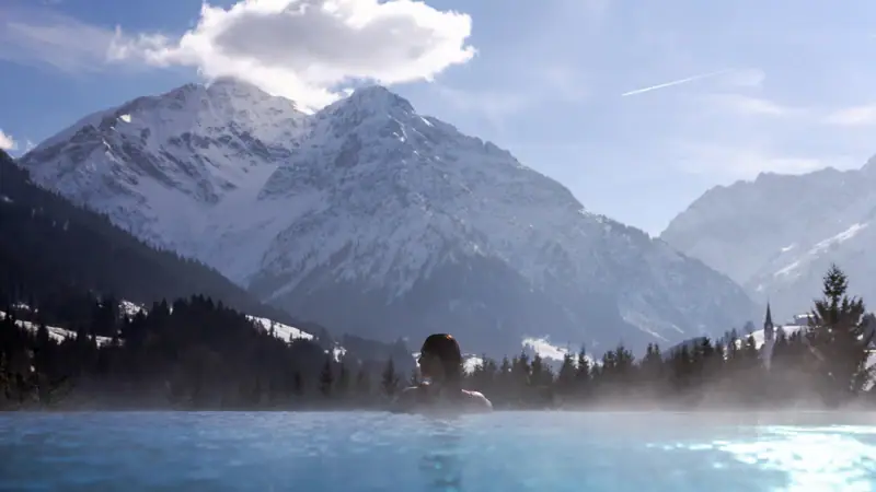 Persona in piscina con montagne sullo sfondo.