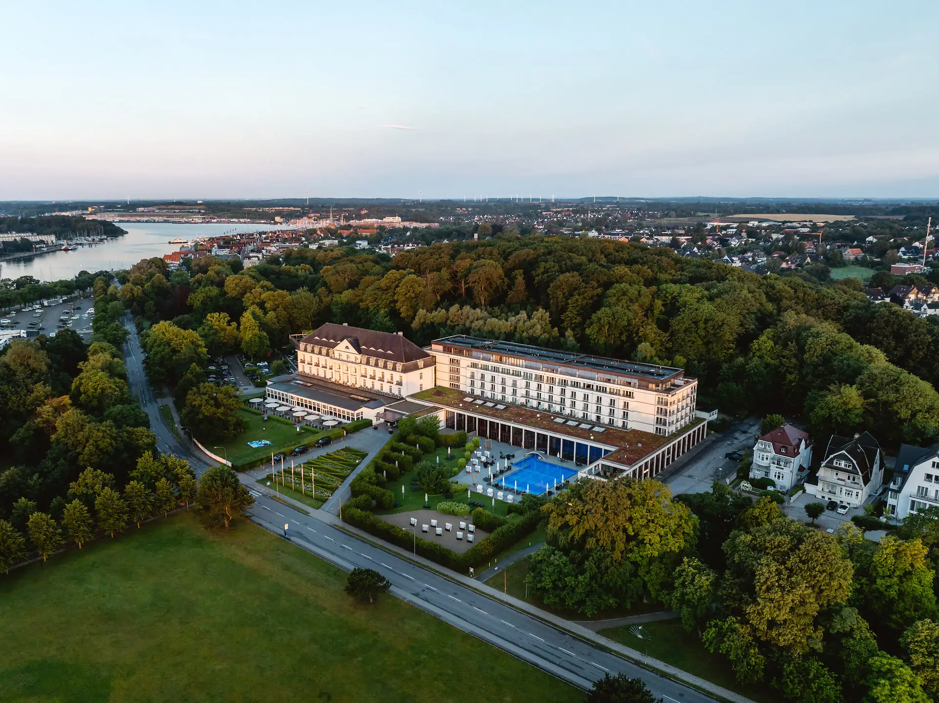 A-ROSA Travemünde Großes Gebäude mit Pool, umgeben von Bäumen.