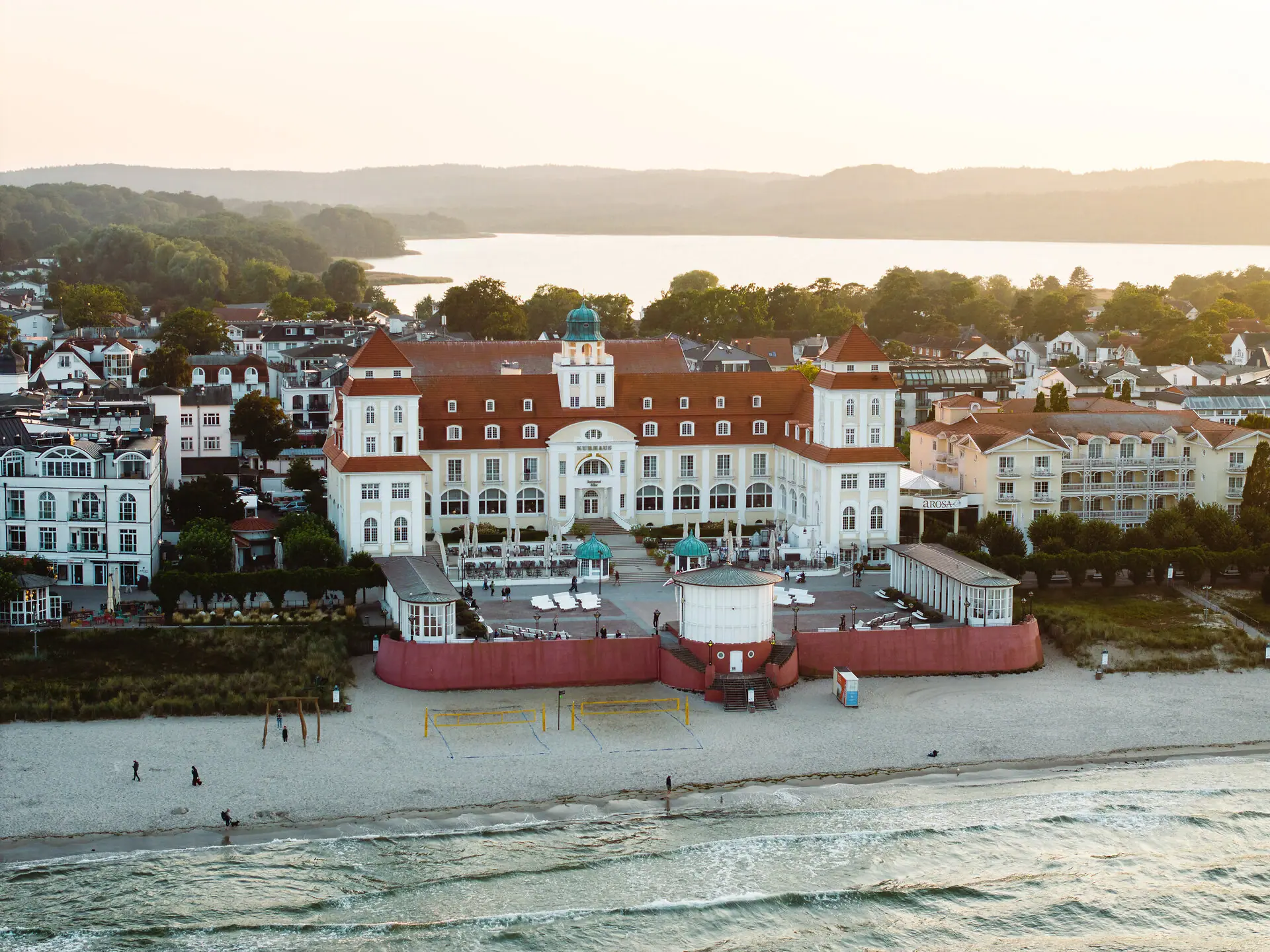 Kurhaus Binz Großes Gebäude mit Strand und Wasser im Hintergrund