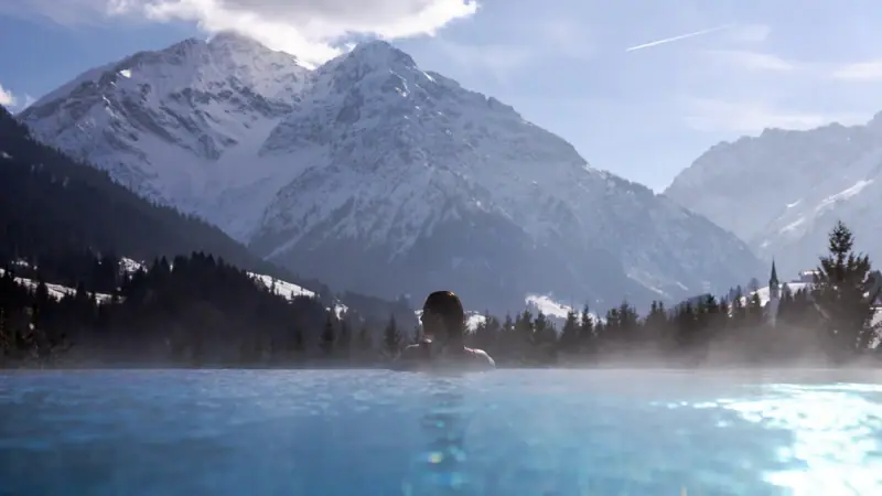 Persona in piscina con montagne sullo sfondo.