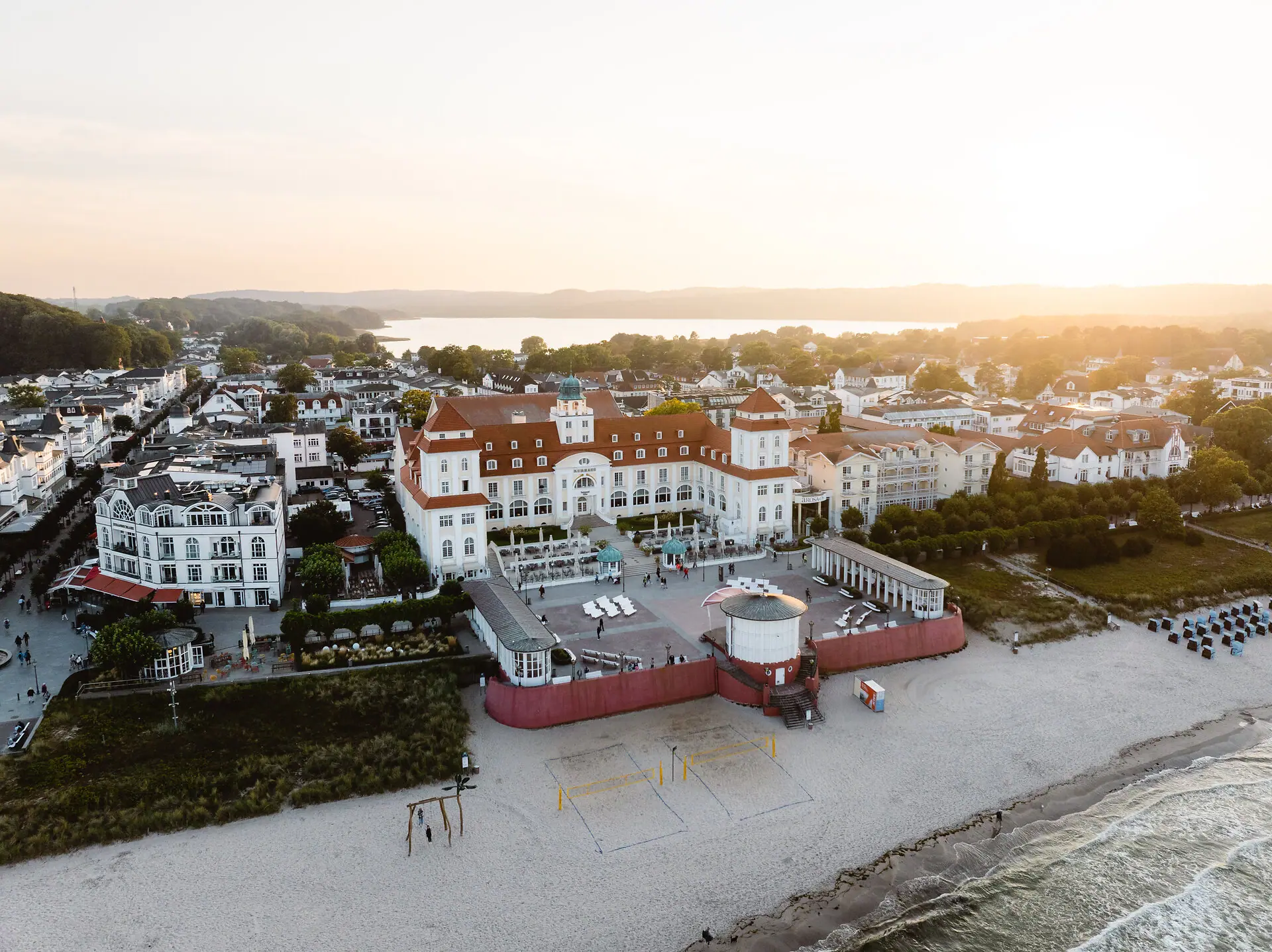 Kurhaus Binz Strand mit Gebäuden und einem Gewässer im Hintergrund.