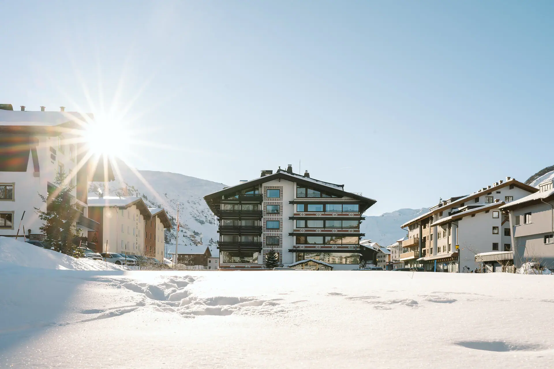 Albergo A-ROSA a Zürs Terreno innevato con edifici e montagne sullo sfondo.