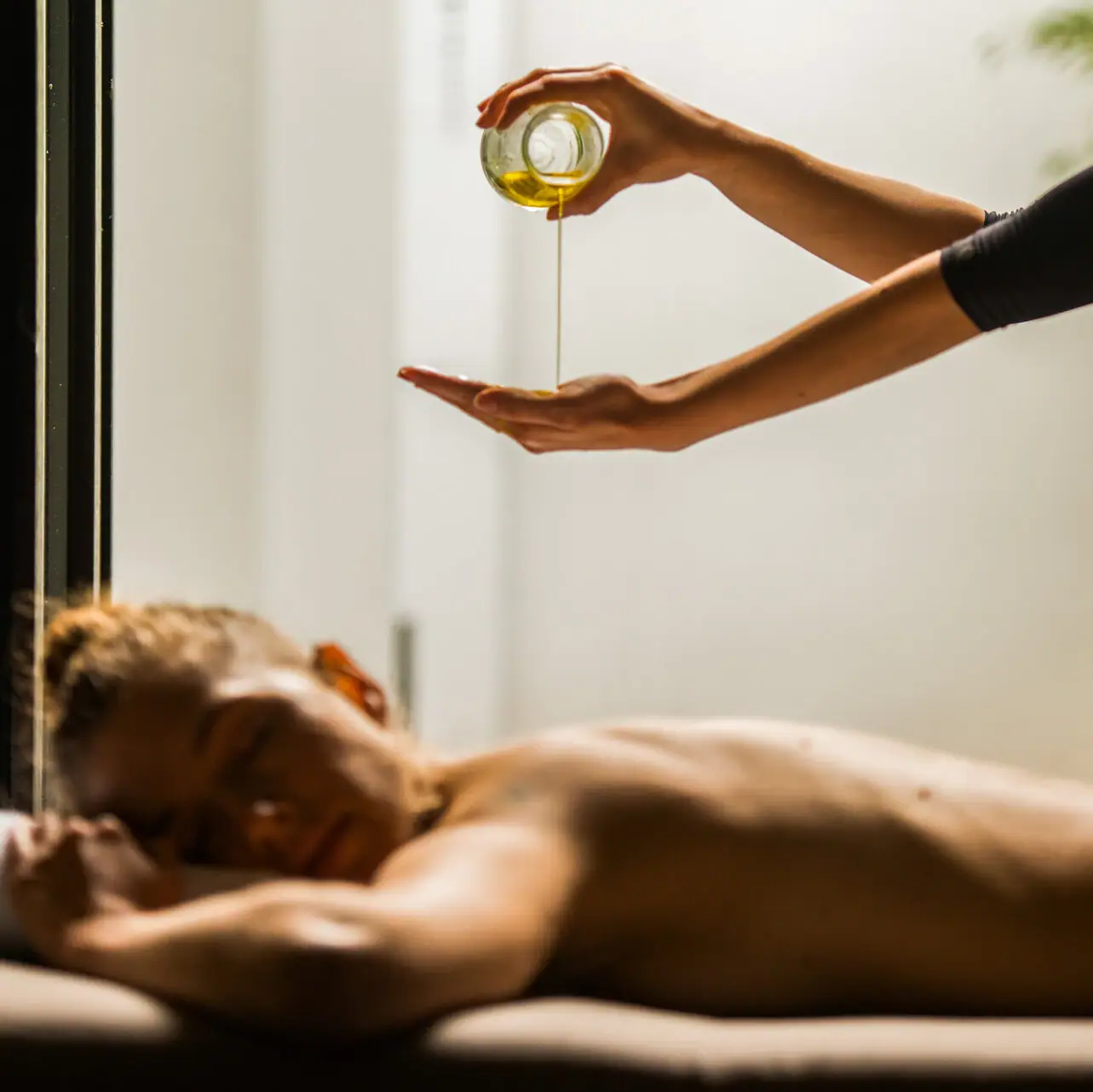 Persona che versa olio nella mano di un'altra persona.